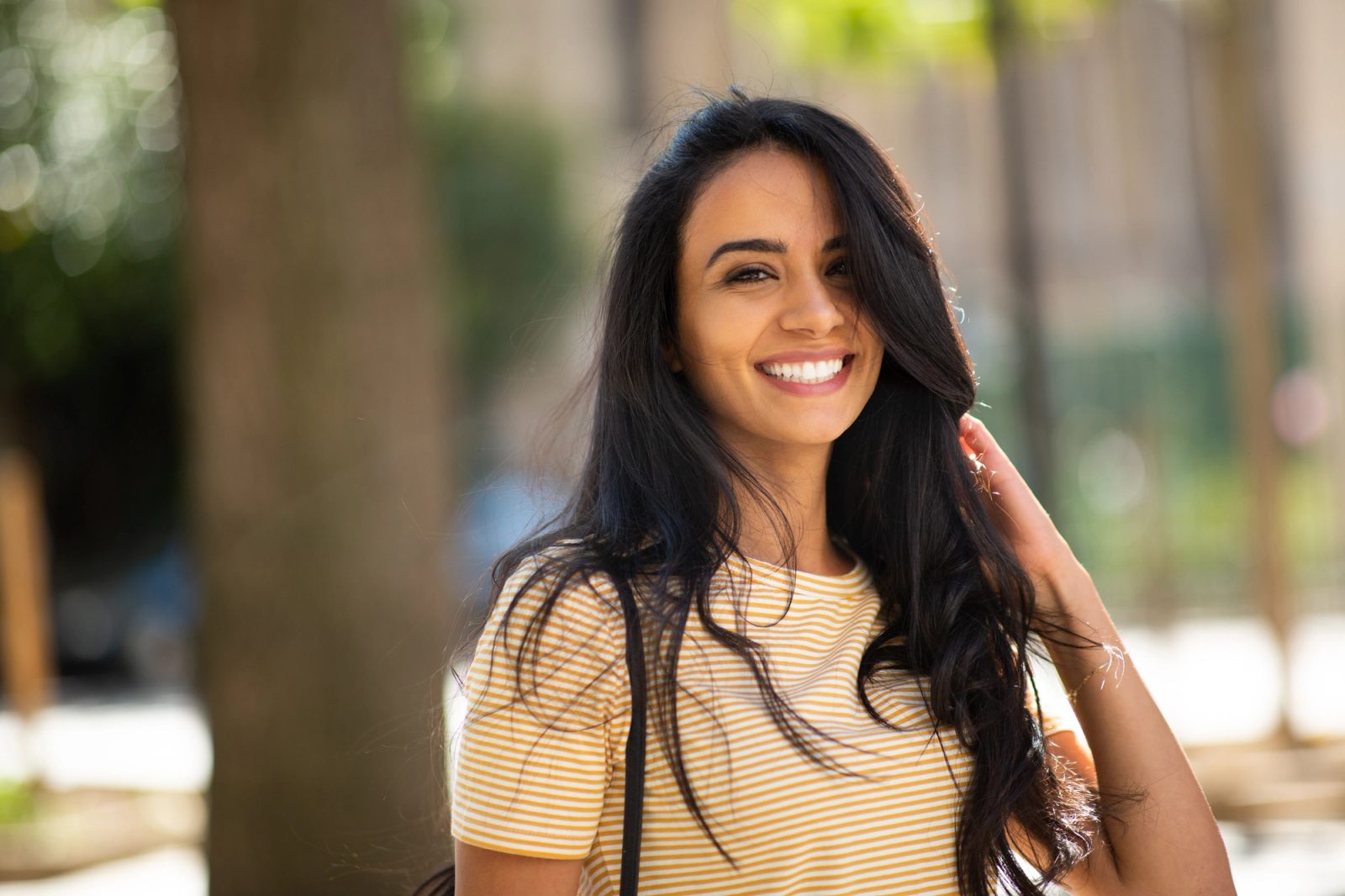 A smiling woman in a yellow striped shirt