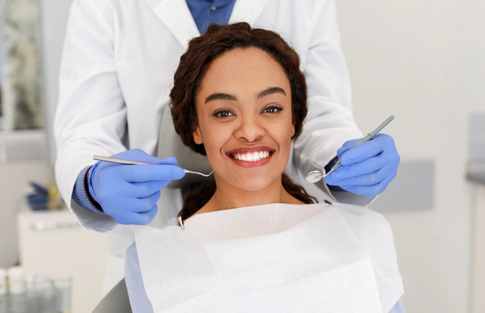 A smiling patient in a dental chair with a dental professional nearby