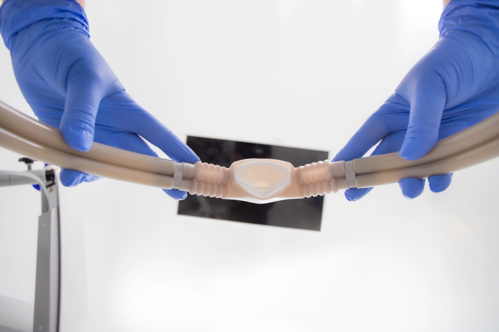 Gloved hands prepare a medical breathing circuit with an oral interface