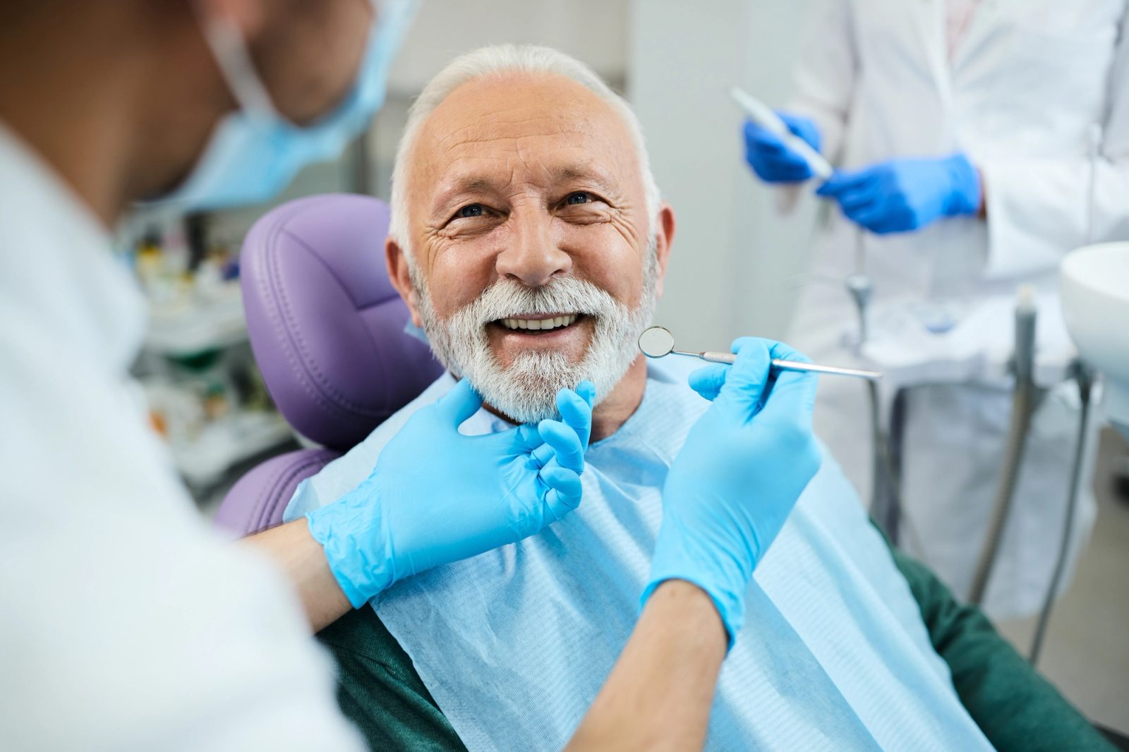 A smiling older man in a dental chair during an examination