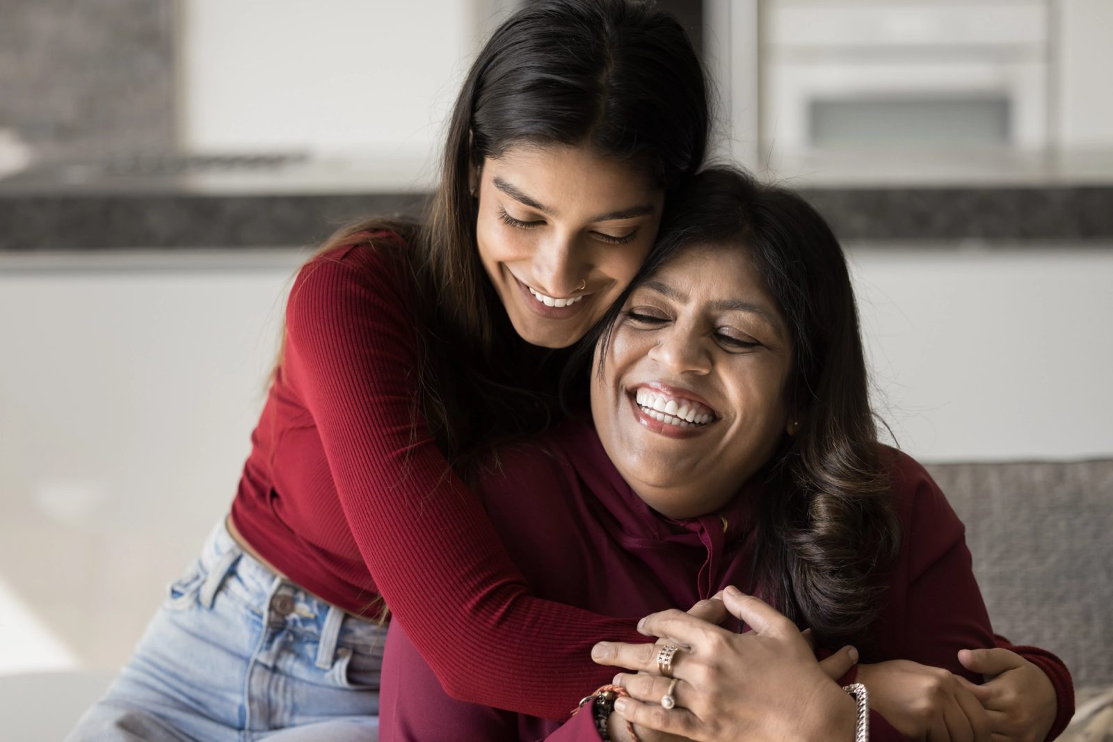 A young woman hugs her mother on a couch