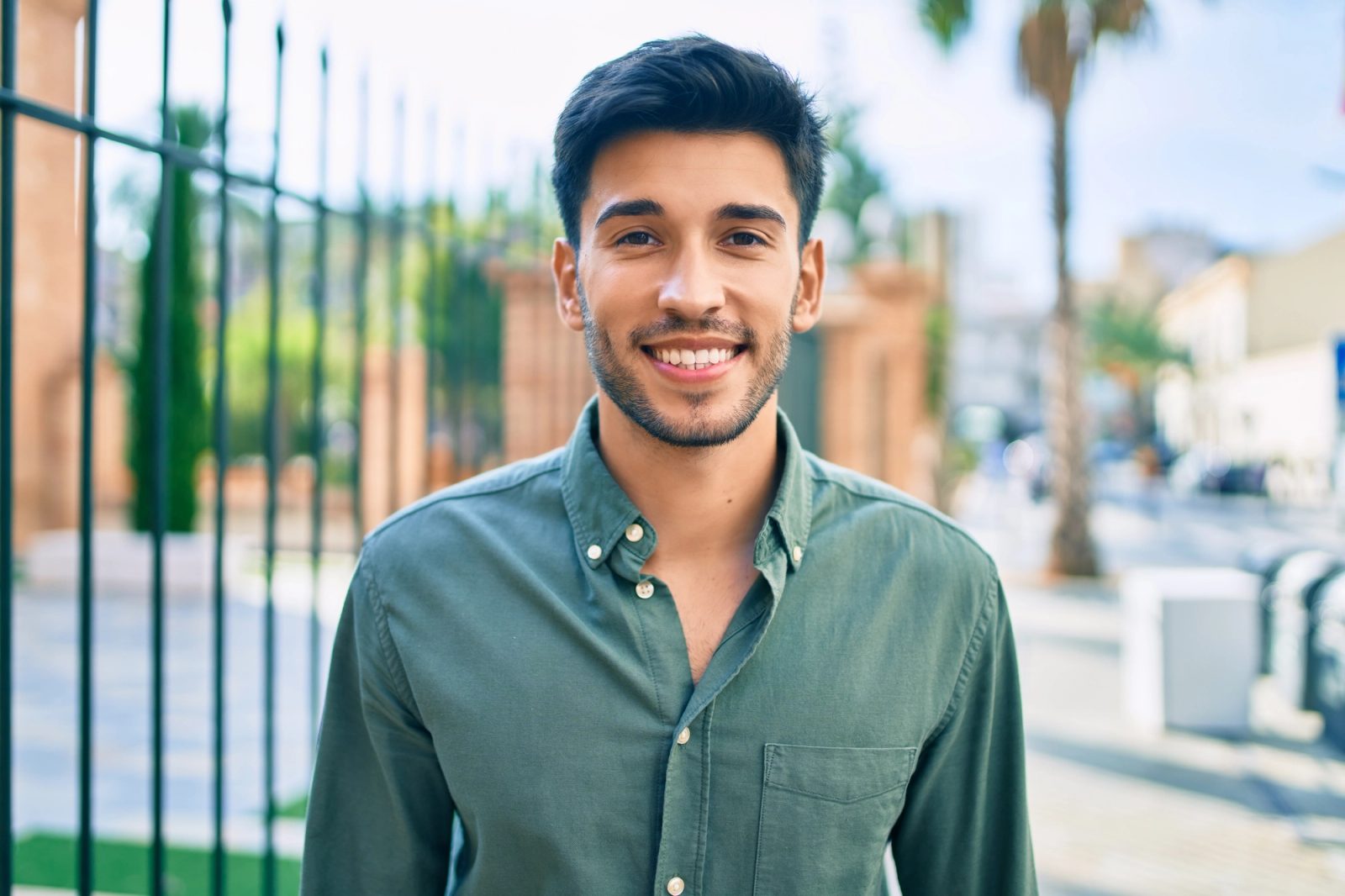 A smiling young man in a green shirt outdoors